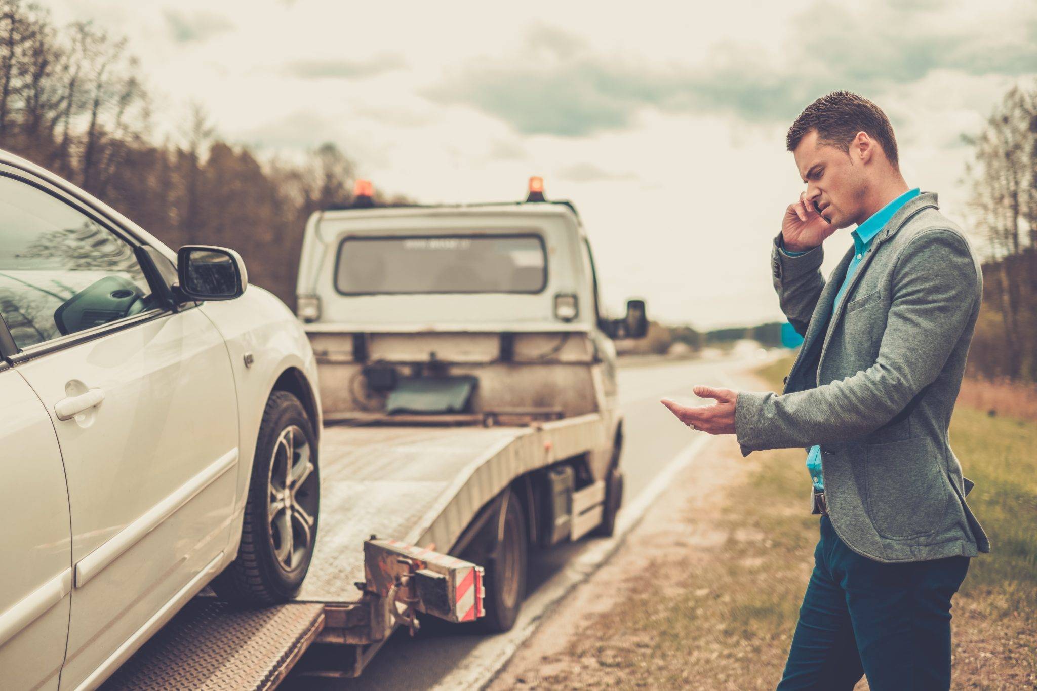 Man Calling While Tow Truck Picking Up His Broken Car